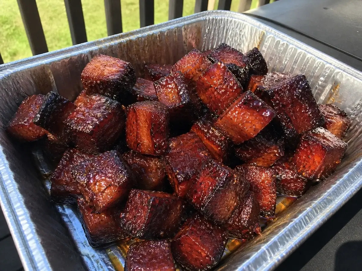 Sticky maple cherry pork belly burnt ends in a tray, cooked low and slow on a BBQ until caramelised and tender