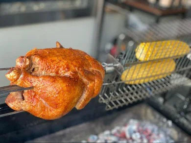 Whole chicken on a rotisserie grill seasoned with Atomic Chicken rub