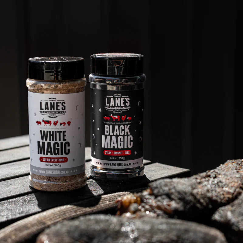 Lane’s White Magic and Black Magic BBQ rub bottles on rustic wood background