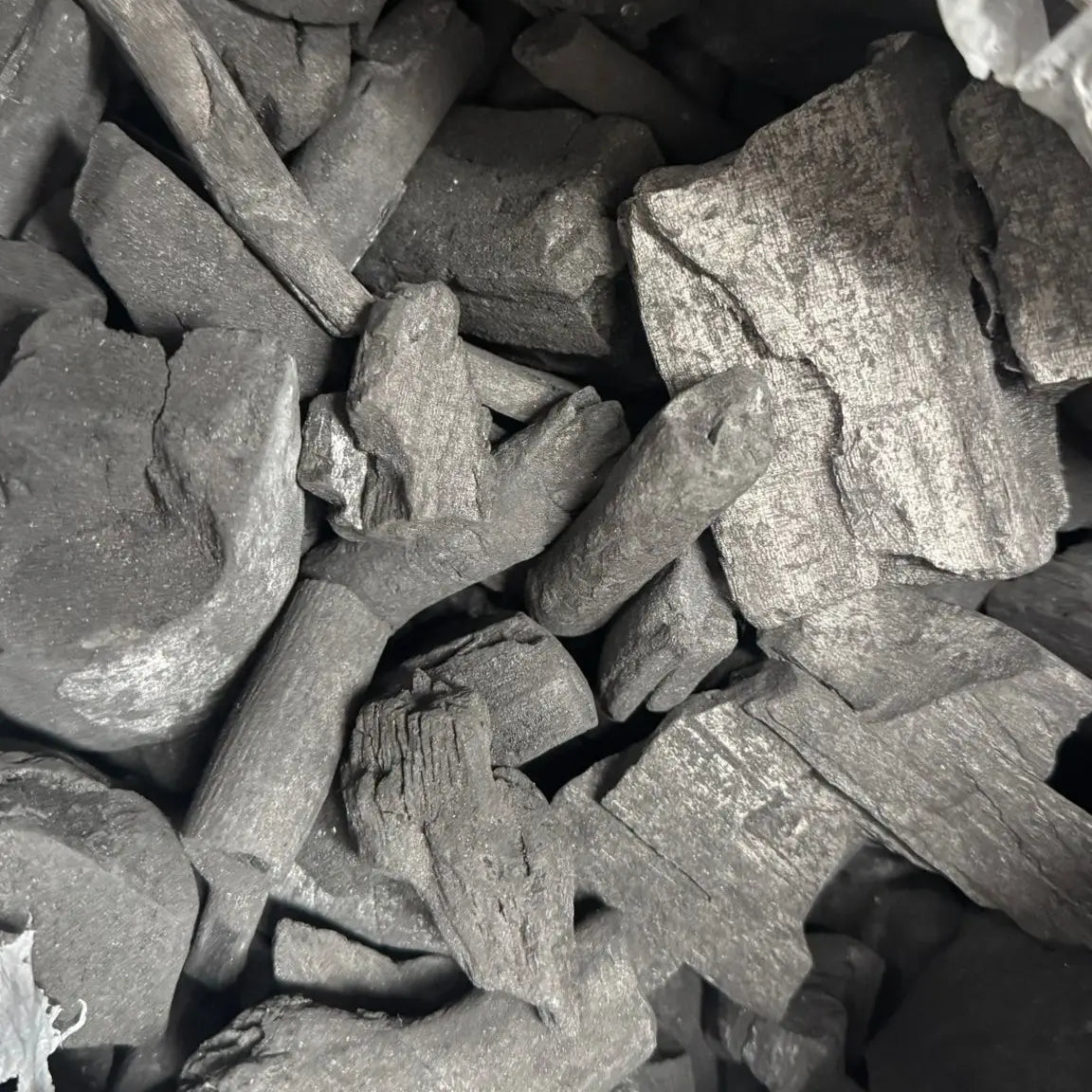 close up of natural lump charcoal pieces inside 10kg bag showing texture and size variation for BBQ use