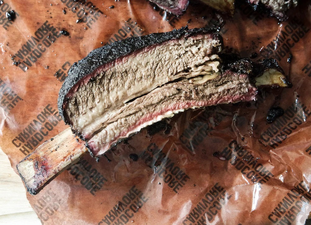 Juicy rib resting on pink BBQ butcher paper post-smoke session