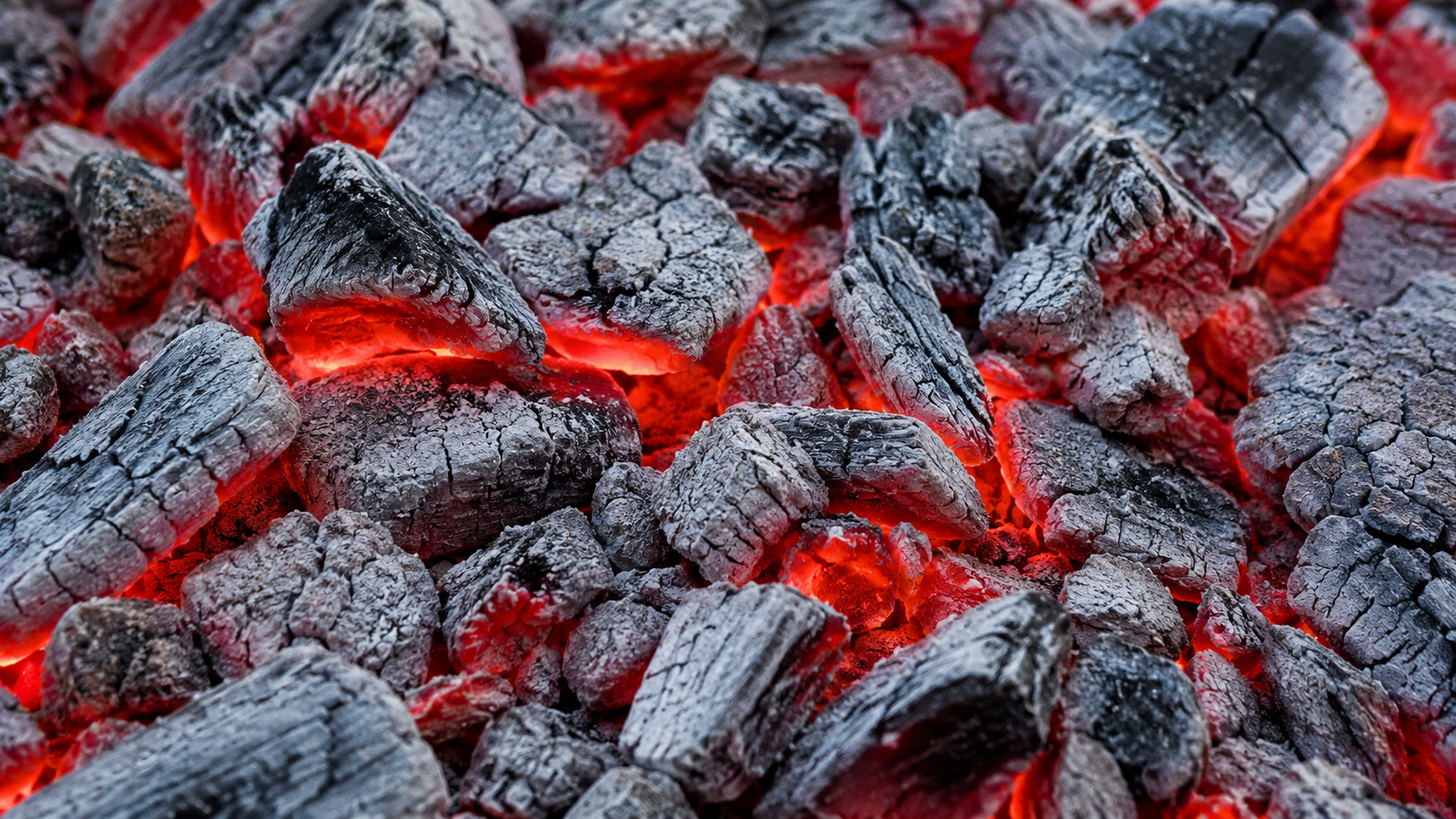 Glowing charcoal embers covered with light grey ash, ready for BBQ cooking 