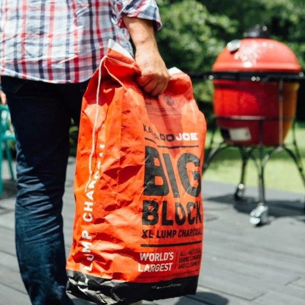 Carrying a bag of Big Block XL lump charcoal to a red Kamado Joe