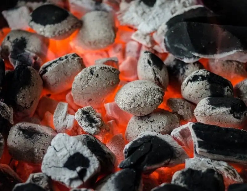 Glowing charcoal briquettes and lump charcoal burning in a BBQ