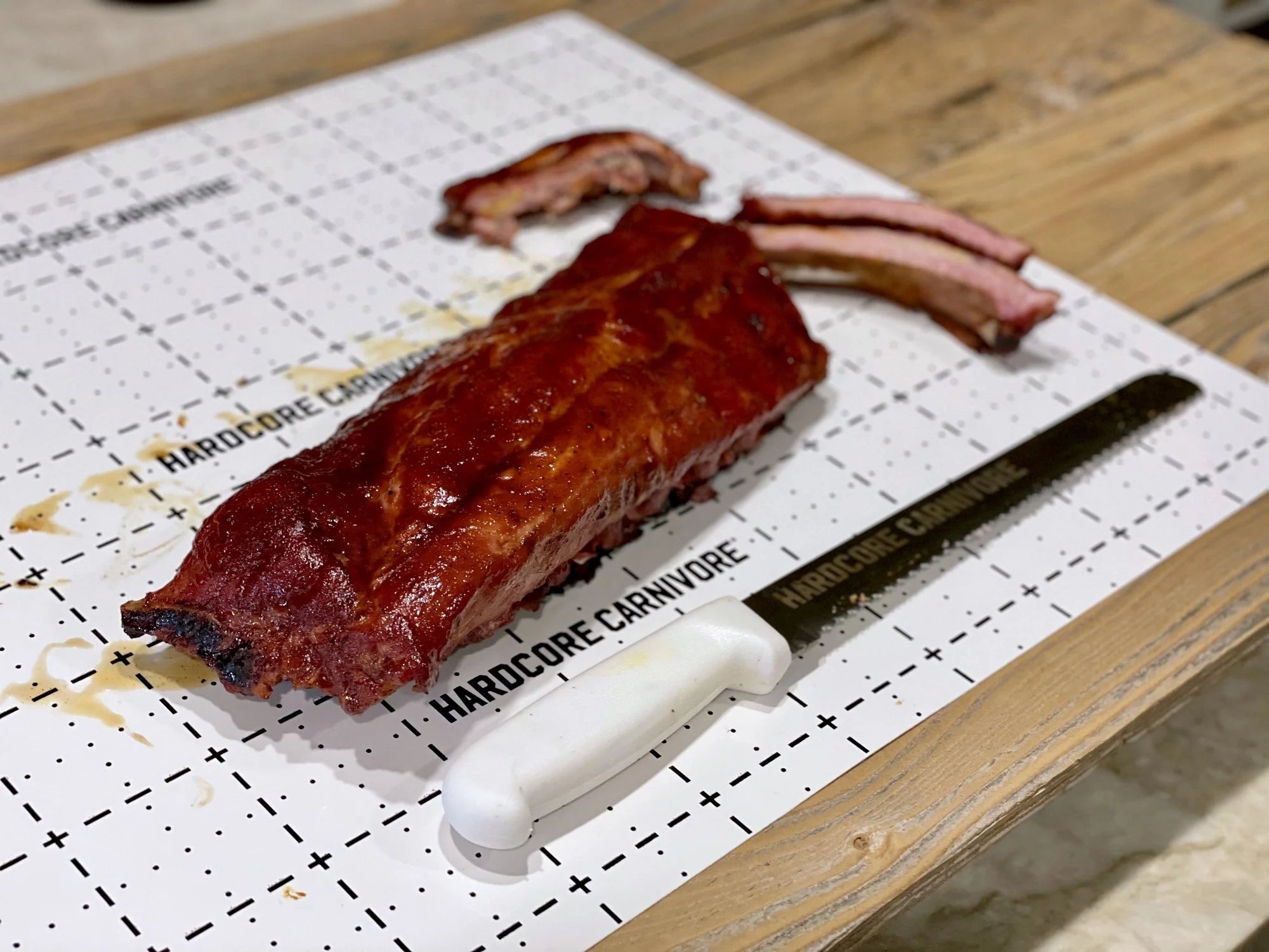 Smoked BBQ ribs on Hardcore Carnivore disposable cutting board with carving knife
