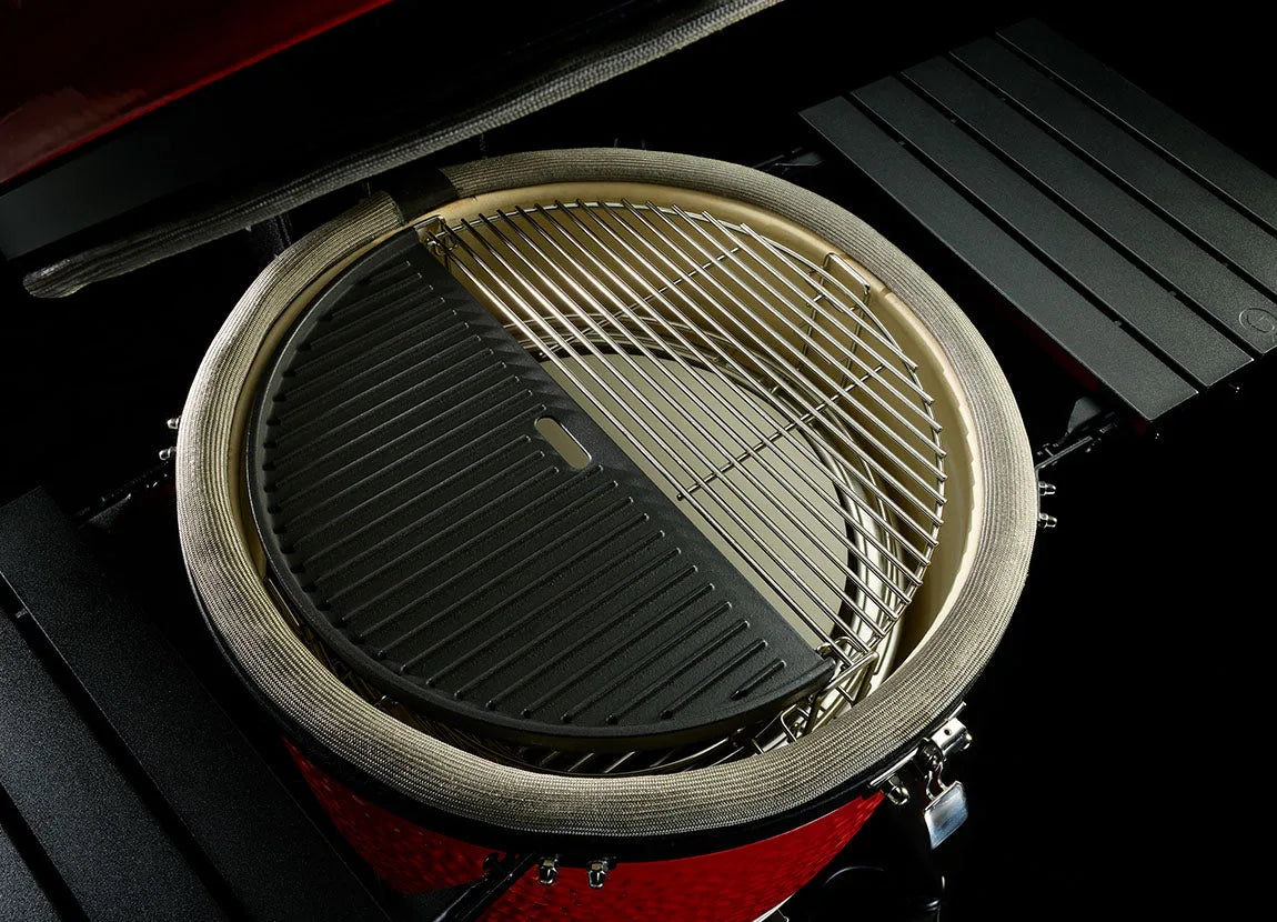 Half moon cast iron griddle sitting next to a cooking grate inside a Kamado Joe