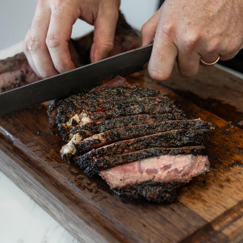 Brisket sliced on a board with dark bark created using Lane’s Black Magic BBQ rub