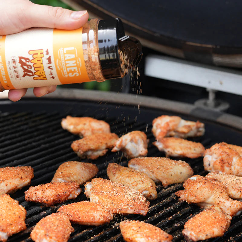 Applying Lane’s Honey BBQ Rub seasoning to chicken wings on grill