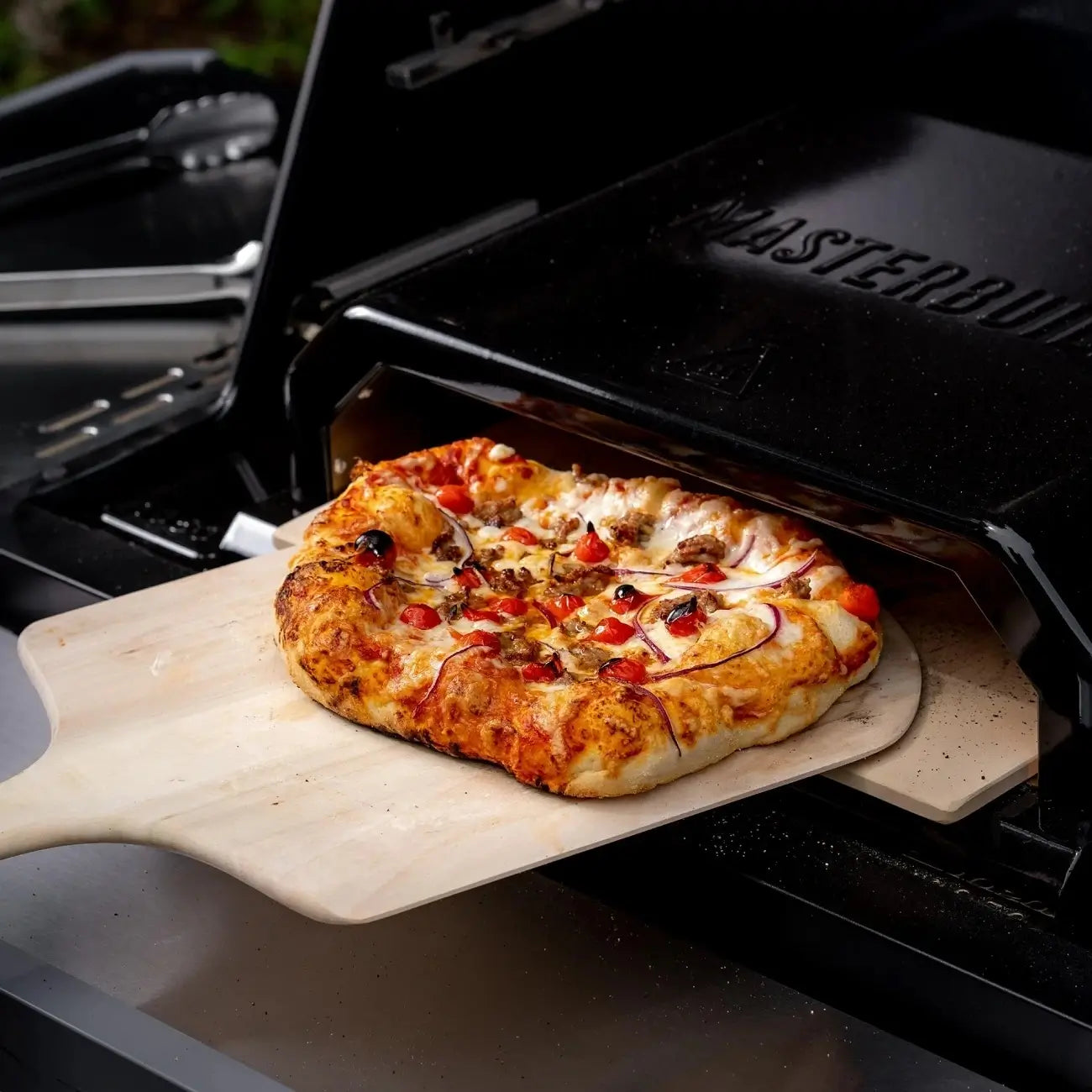 Fresh pizza cooked inside the Masterbuilt pizza oven attachment on a BBQ