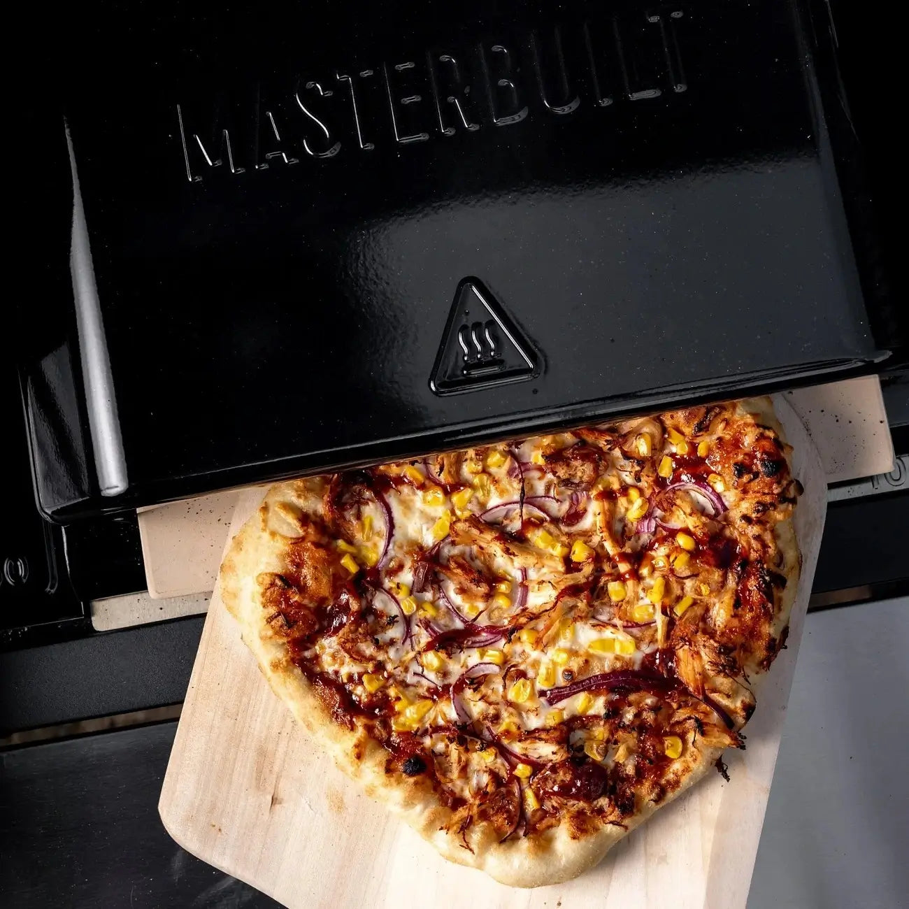 Removing pizza from the Masterbuilt pizza oven attachment using a pizza peel