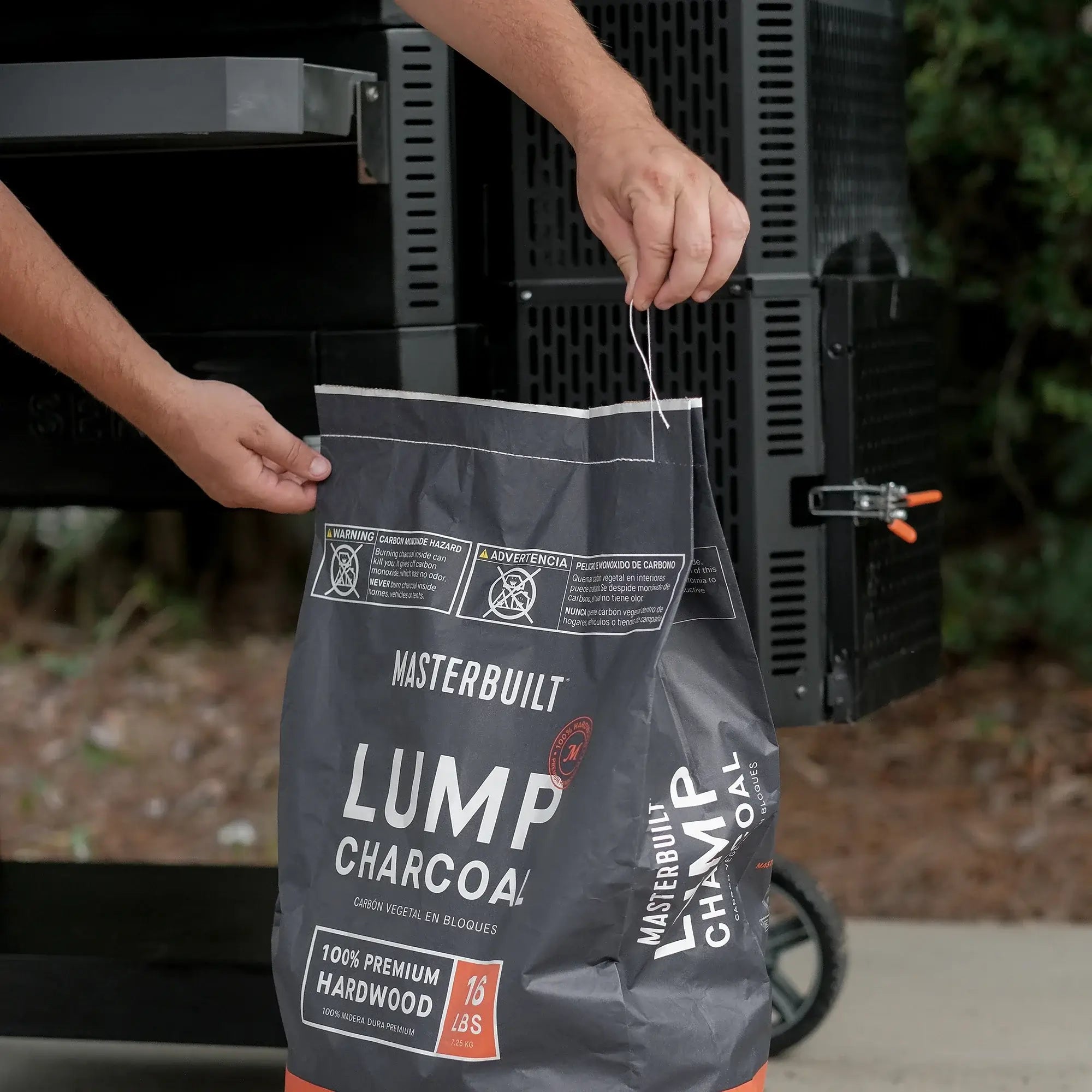 Easy open Masterbuilt Premium Hardwood Lump Charcoal bag beside the Gravity Series charcoal hopper before loading fuel.