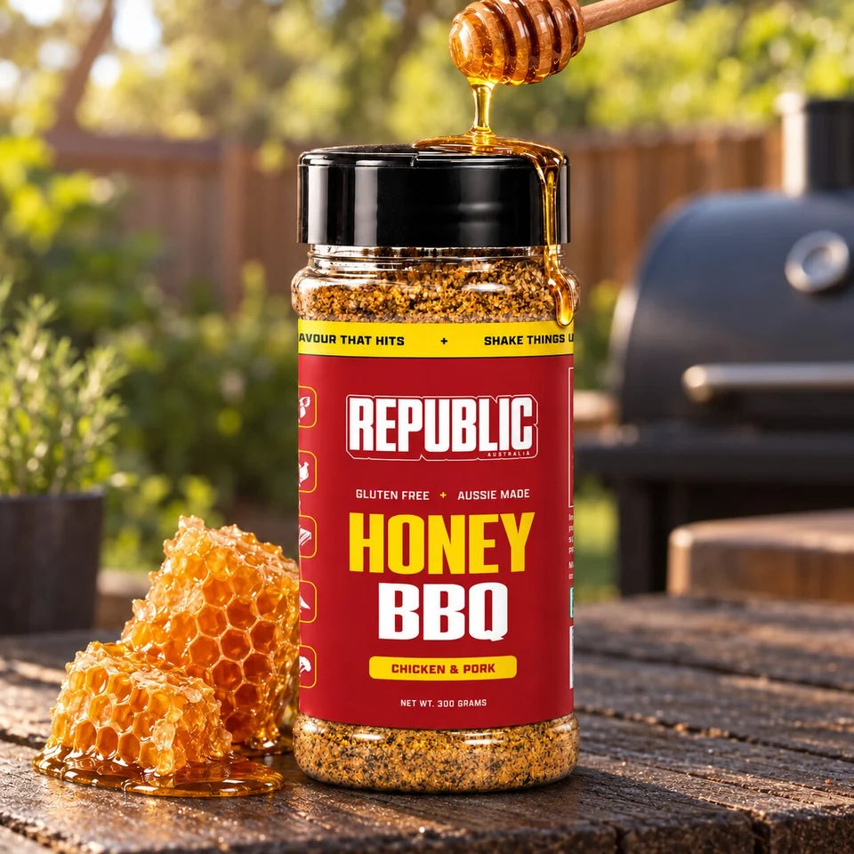 Republic Honey BBQ Chicken and Pork Seasoning jar outdoors with honeycomb and honey beside a barbecue