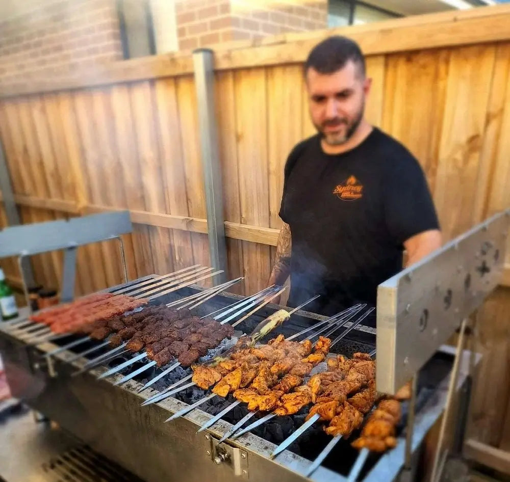 Man grilling chicken skewers on XL rotisserie BBQ